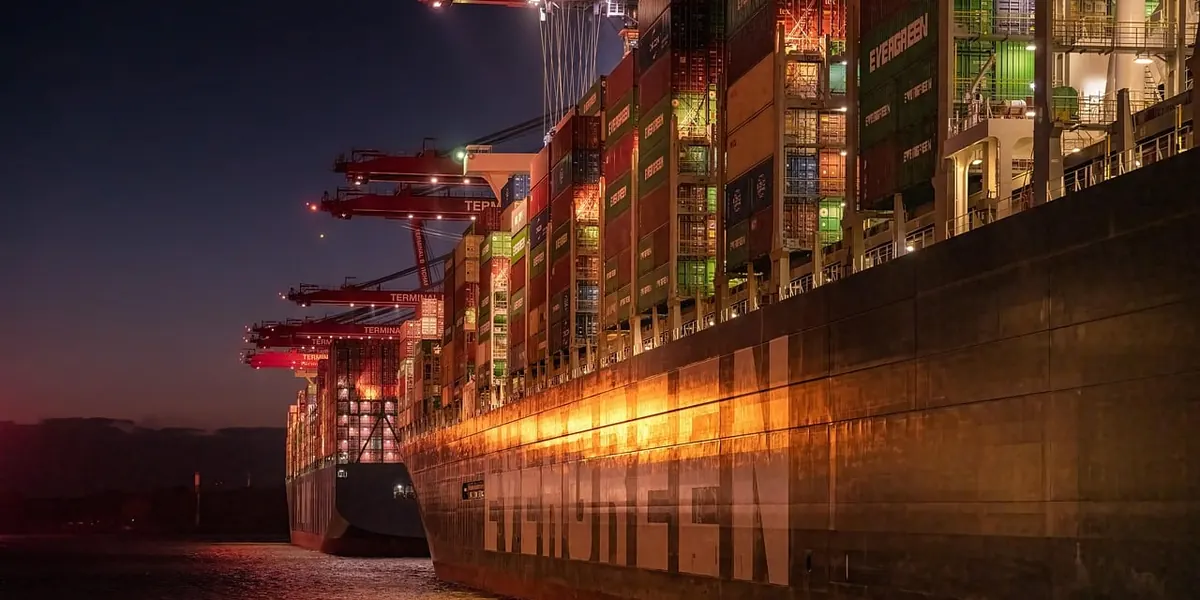 Container ship loaded with containers at a port with cranes at night