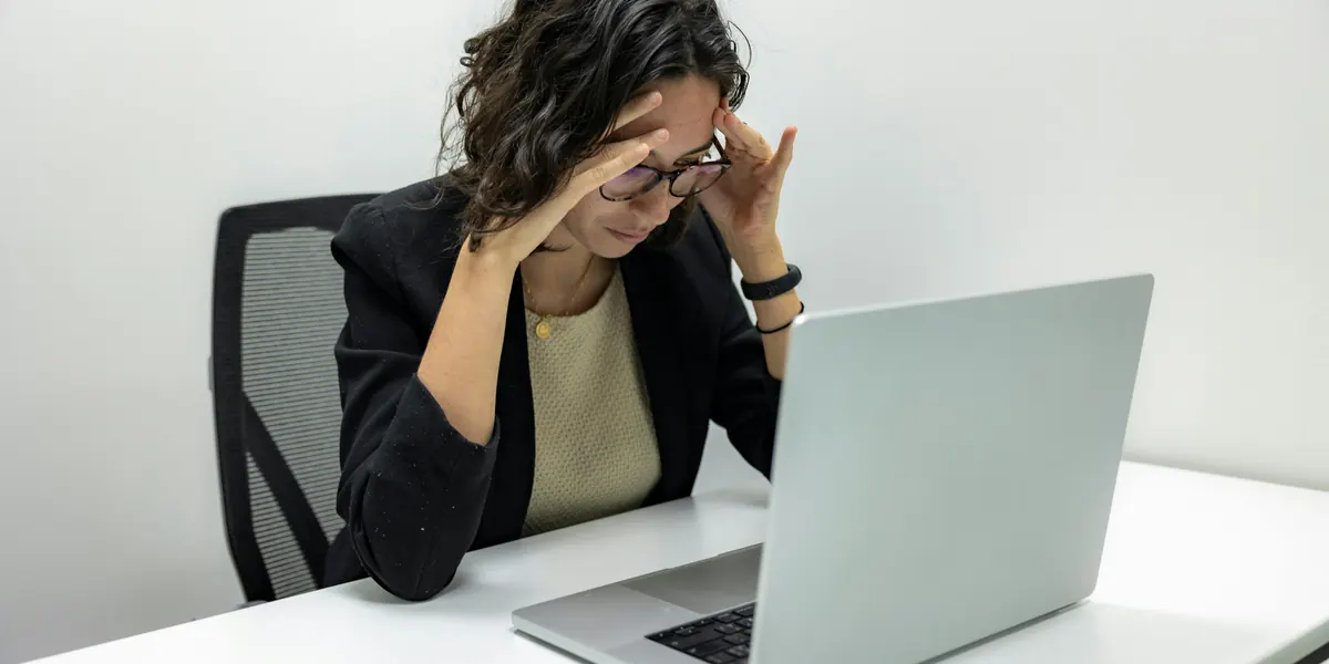 Stressed woman with her hands on her head in front of a laptop