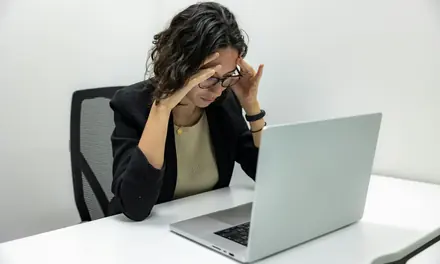 Stressed woman with her hands on her head in front of a laptop