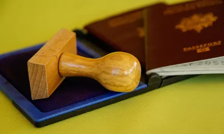 Wooden rubber stamp and passports on a yellow surface